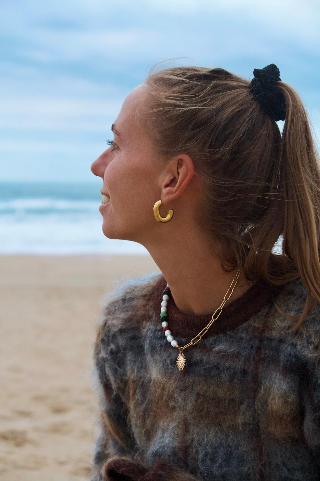 Collier fait main en pierres naturelles porté sur un modèle portant un pull d'hiver