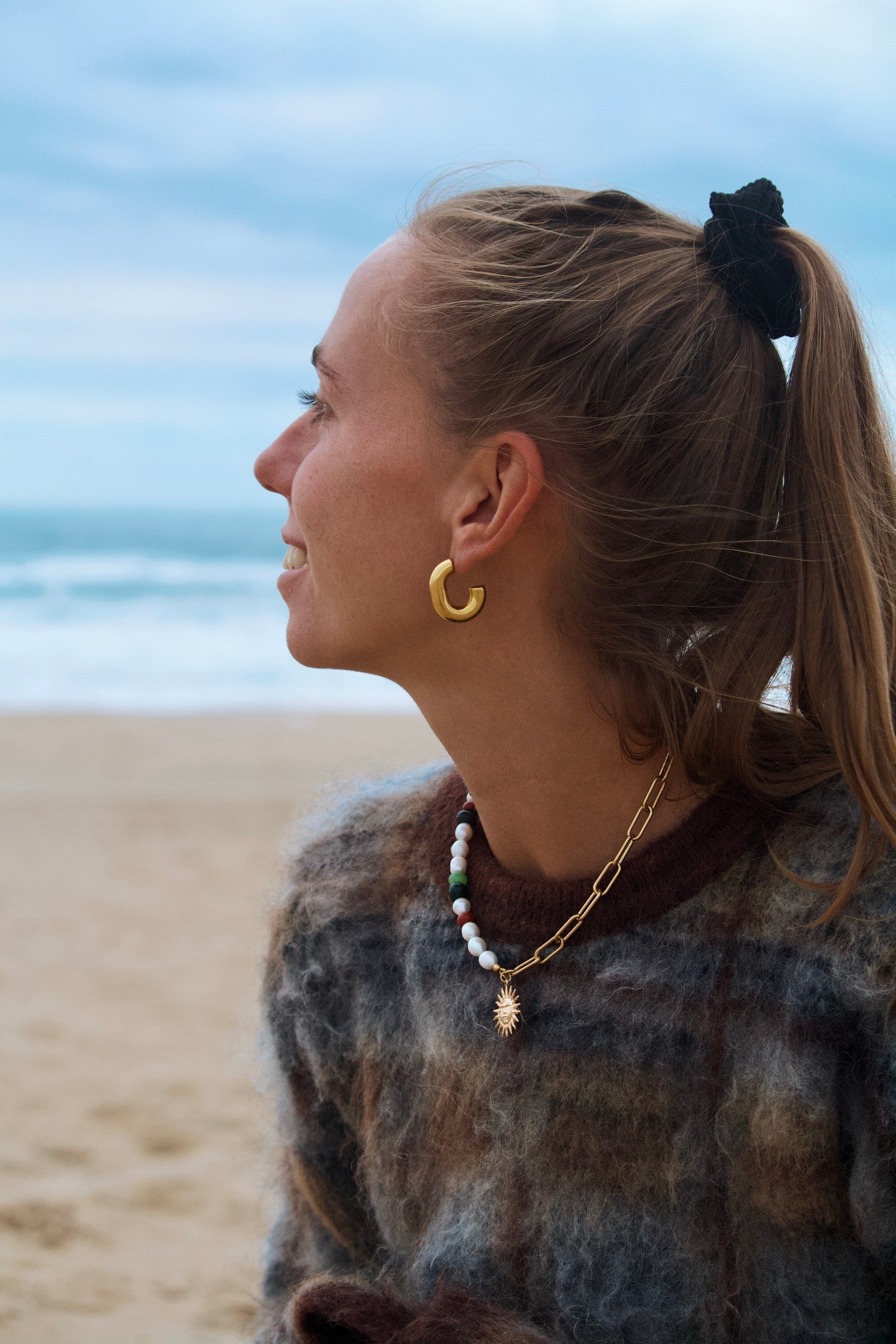 Collier fait main en pierres naturelles porté sur un modèle portant un pull d'hiver