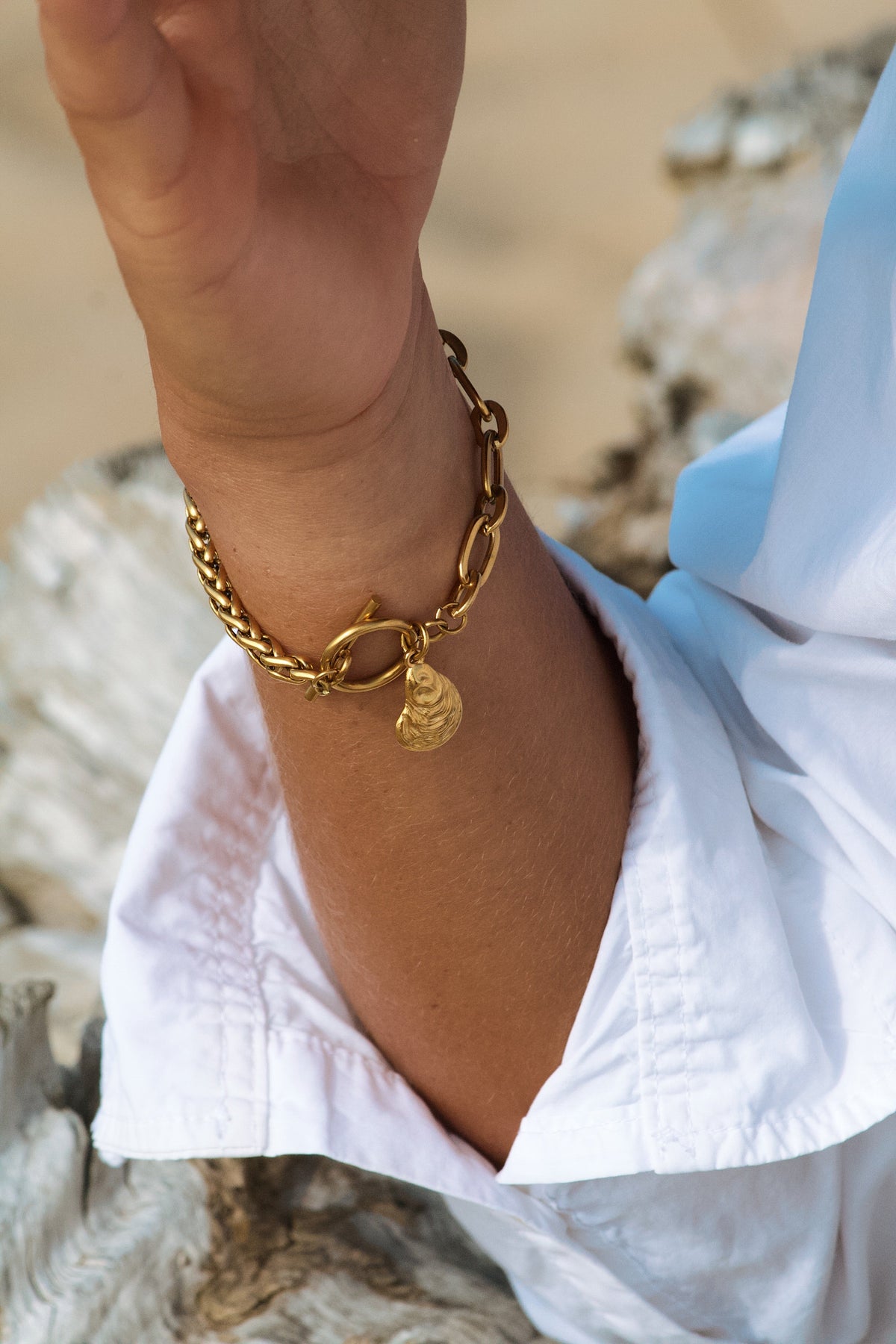 bracelet doré fait main en acier inoxydable porté par une modèle sur une plage dans les landes