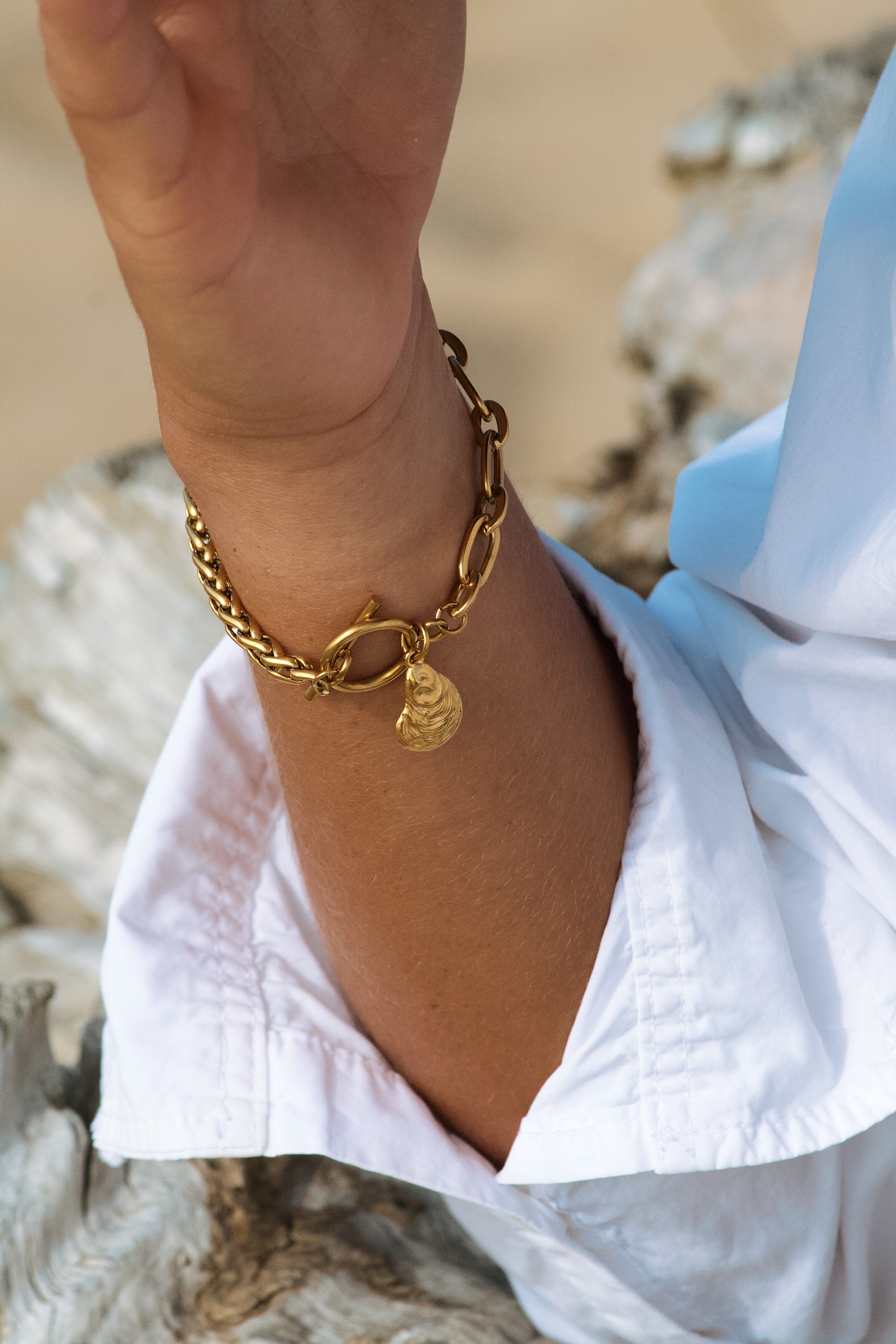 bracelet doré fait main en acier inoxydable porté par une modèle sur une plage dans les landes